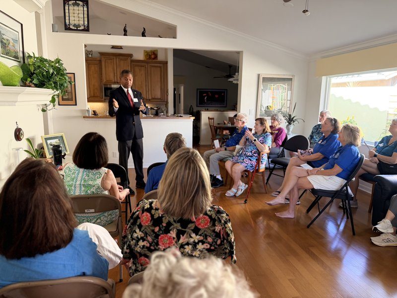 Victor Arias speaking to a seated audience at a community house party in Southwest Florida